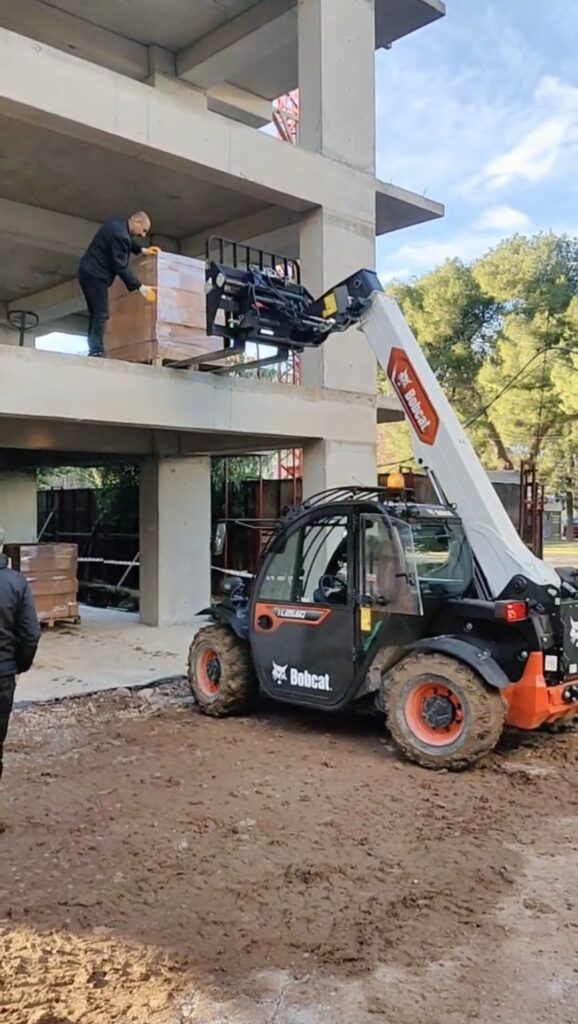 İzmir'de yüksek katlı bina inşaatına Manitou vinç kullanarak tuğla ve çatı malzemesi çıkarma hizmeti.