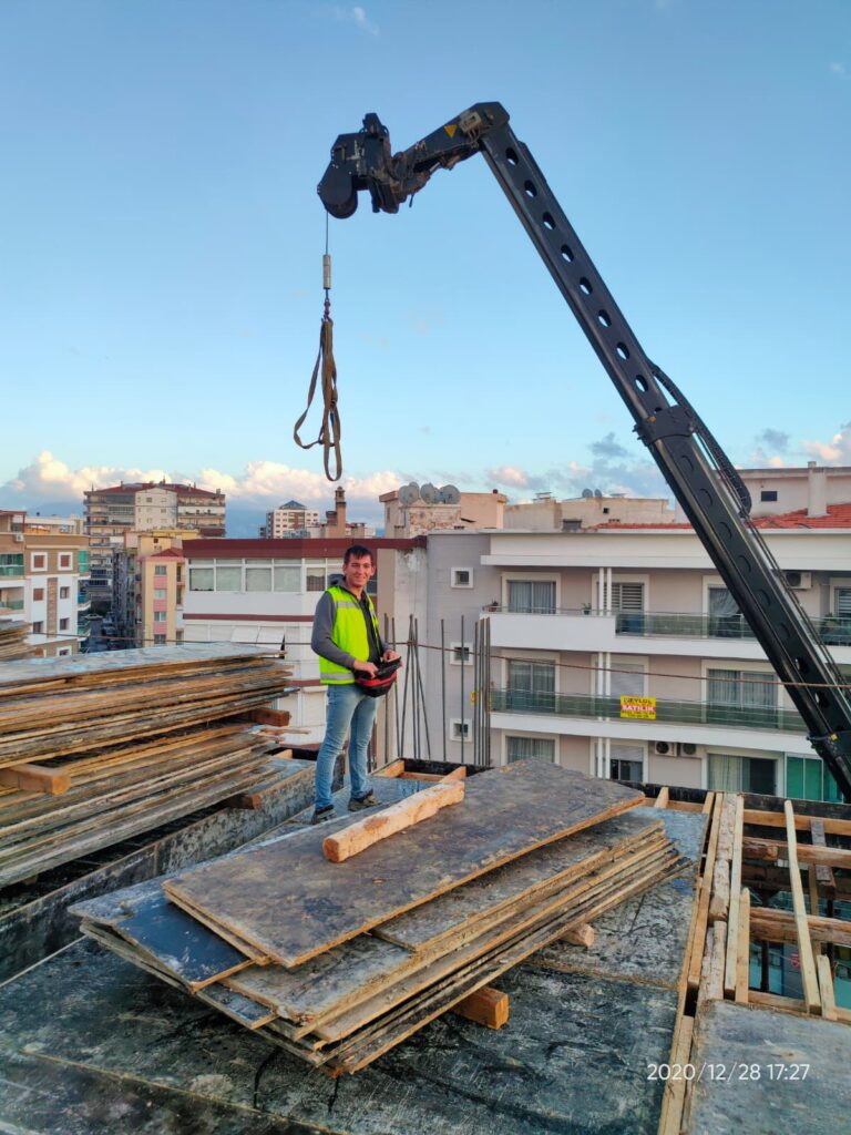 İzmir şehir manzarası eşliğinde çatı katında malzeme alımı yapan operatör ve vinç çalışması.