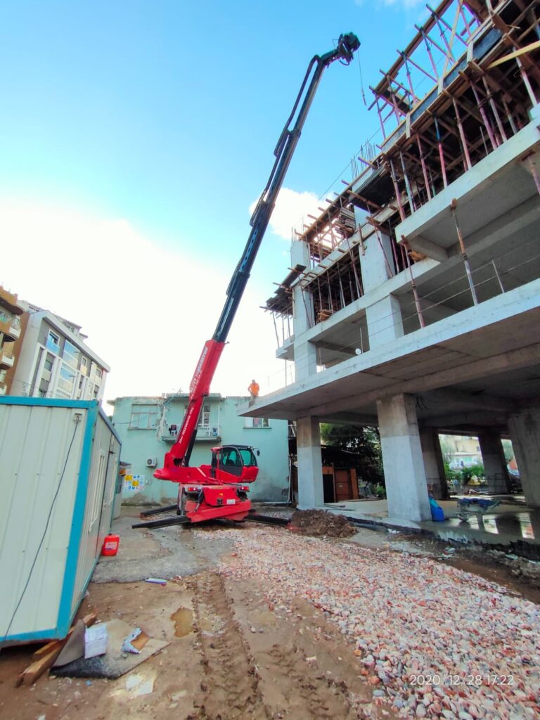 İnşaat halindeki binanın en üst katına malzeme ulaştıran uzun bumlu Manitou kiralık vinç.
