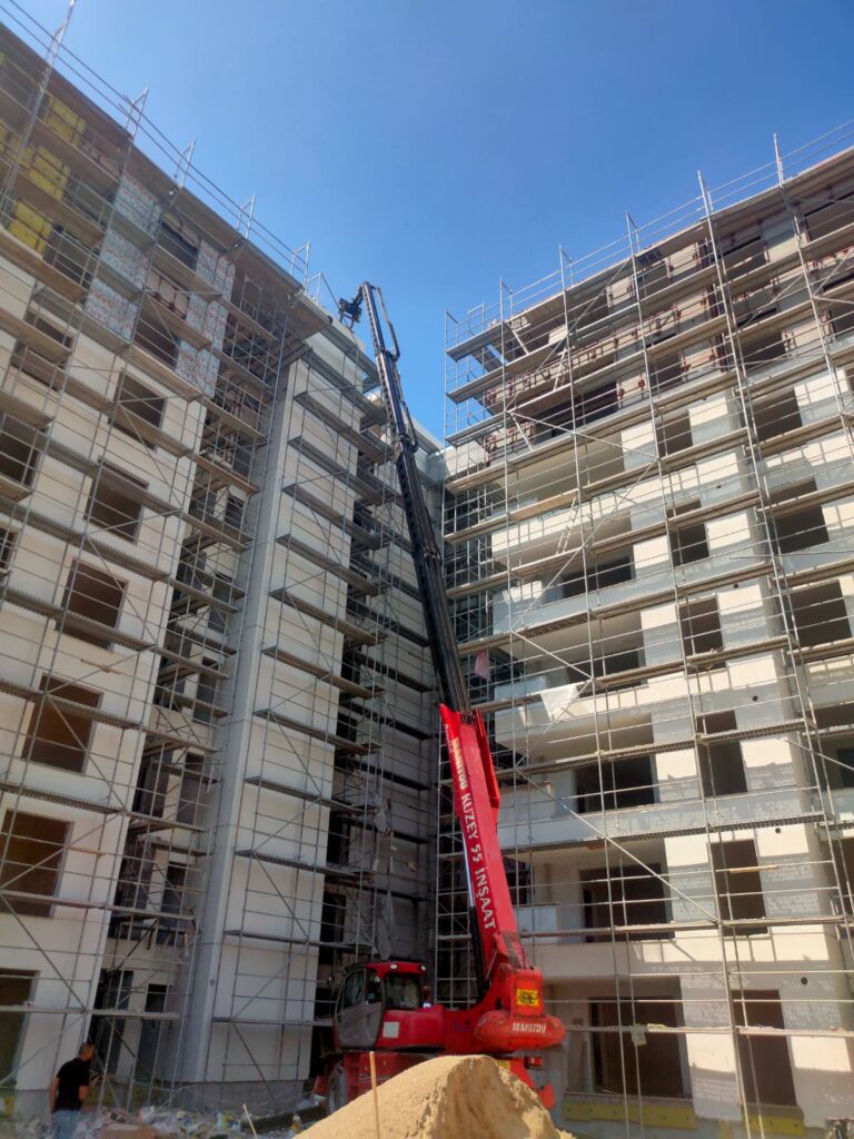 İzmir'de şantiye sahası içinde binalar arasına kurulan iskeleye erişim sağlayan kiralık Manitou vinç.