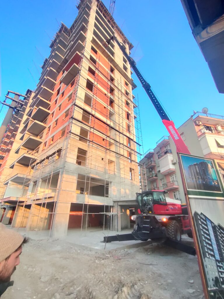İzmir'de devam eden yüksek katlı konut projesinde çalışan kiralık Manitou ve proje görseli.