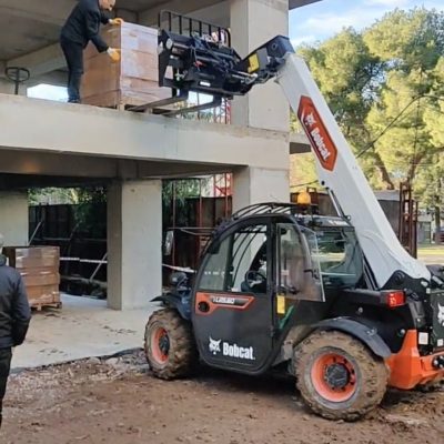 İzmir'de yüksek katlı bina inşaatına Manitou vinç kullanarak tuğla ve çatı malzemesi çıkarma hizmeti.